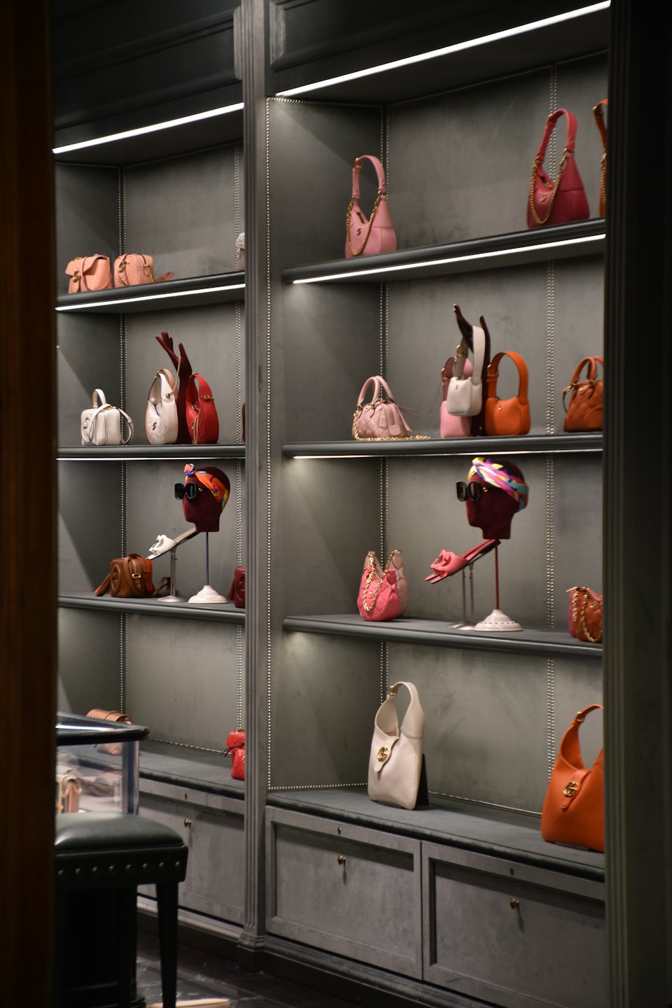 Borse e accessori di lusso esposti su scaffali illuminati di boutique.