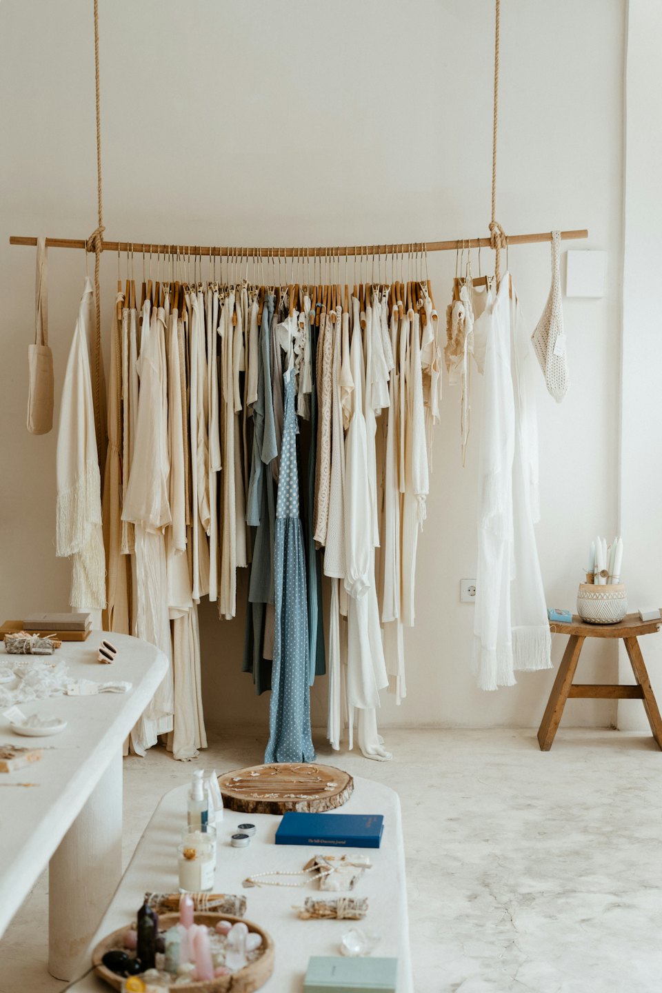 Interno di una boutique con appendiabiti in legno e tavoli espositivi.