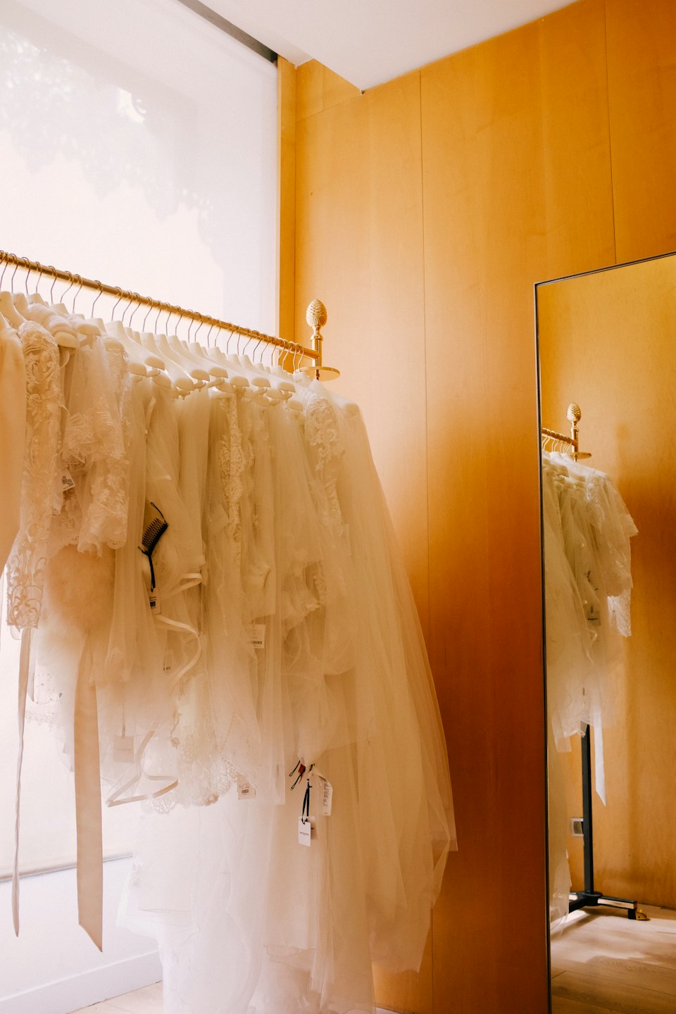 Eleganti abiti da sposa pendono da un appendiabiti dorato in una boutique.